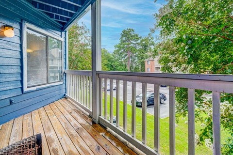 A balcony with a wooden floor and a white railing.