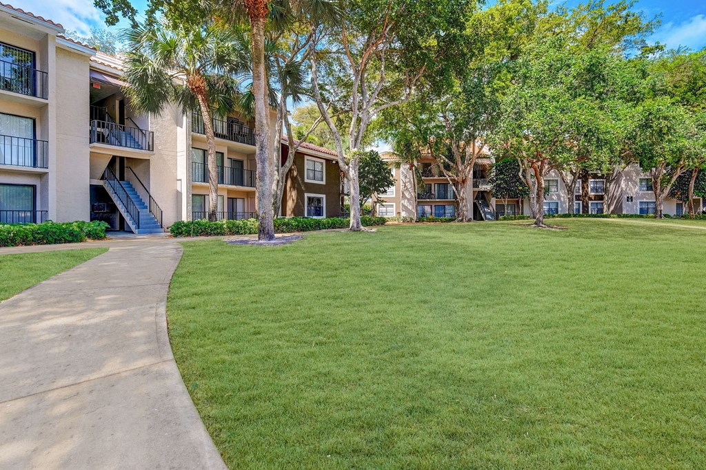 a grassy area with trees and apartment buildings in the background