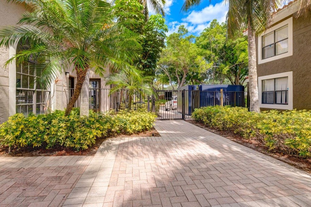 a pathway with palm trees and buildings in the background