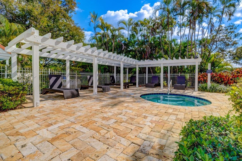 a patio with a hot tub and a pergola