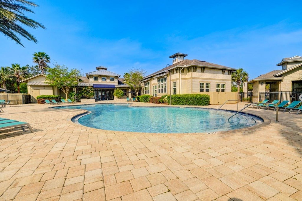a swimming pool with lounge chairs and houses in the background