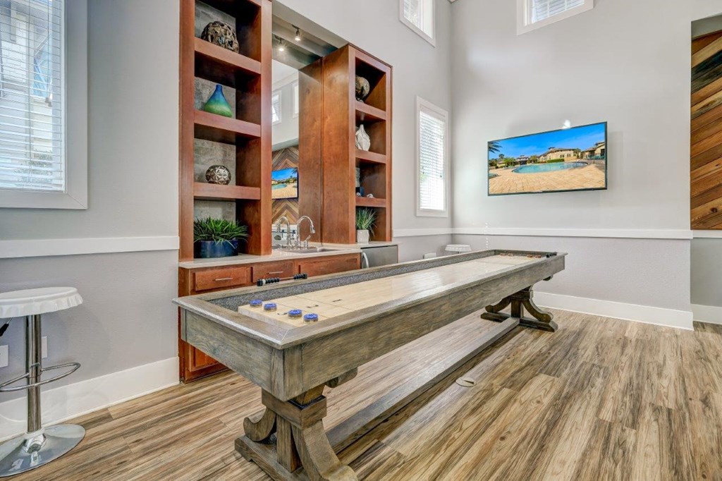 a game room with a shuffleboard table and a tv