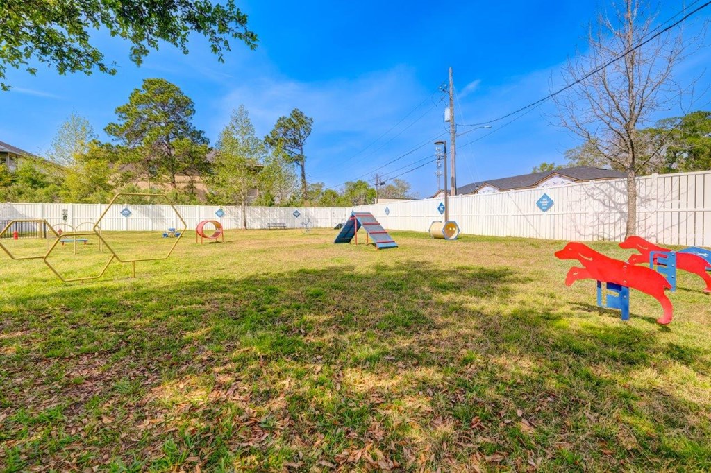 a large grassy area with a playground in front of a fence
