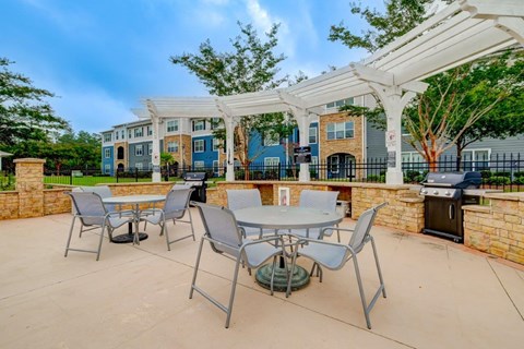 an outdoor patio with tables and chairs and a grill