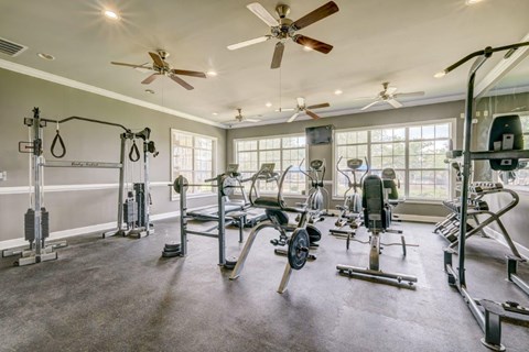 a gym with weights and other equipment and windows