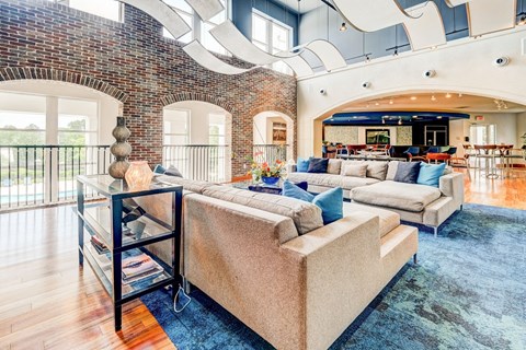 a living room with a large couch and a brick wall