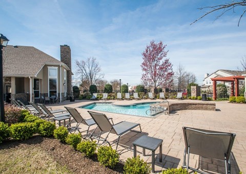 A backyard with a pool and lounge chairs.