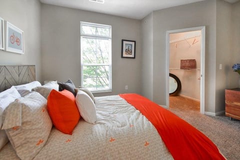A bedroom with a bed covered in a white and orange comforter.