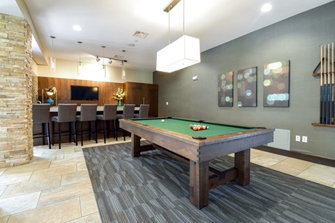 A pool table is in the middle of a room with a stone pillar.