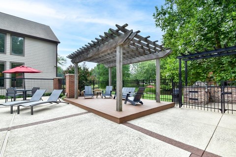 A patio with a pergola and chairs.