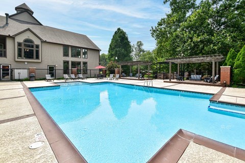 A large swimming pool in front of a building with a covered area.