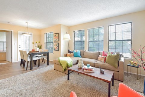 A living room with a couch, chairs, and a dining table.