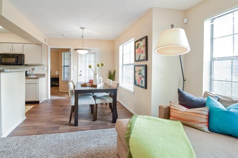 A well-lit living room with a dining table and chairs.