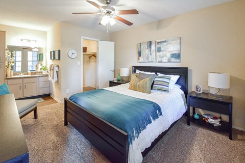 A bedroom with a bed, a ceiling fan, and a nightstand.