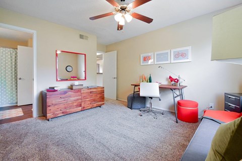 A room with a ceiling fan and a desk with a computer.