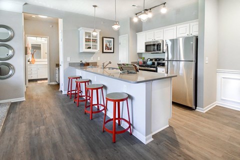 A kitchen with a white counter and red stools.