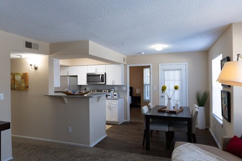 A well-lit kitchen with a dining table and chairs.