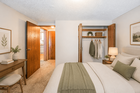 A bedroom with a bed, desk, and chair.