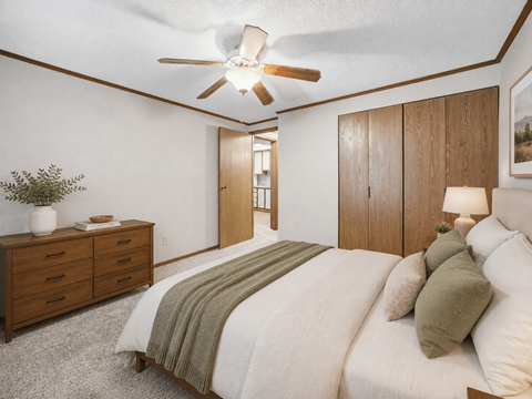 A bedroom with a bed, dresser, and ceiling fan.