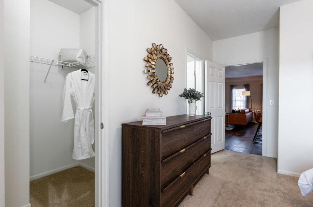 a bedroom with a dresser and a robe hanging on the wall