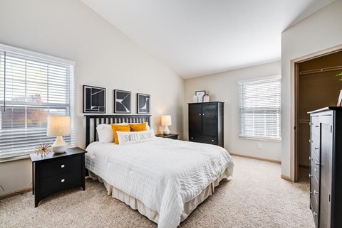 a bedroom with a large bed and two windows