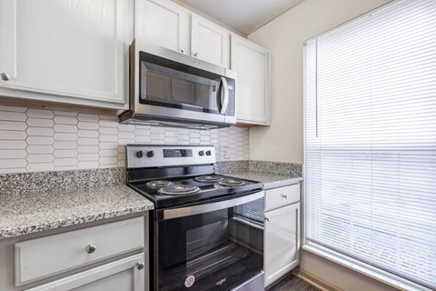 A kitchen with a black stove top oven and white cabinets.