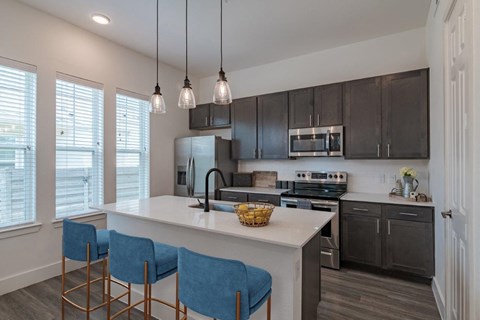a kitchen with a large island with blue chairs