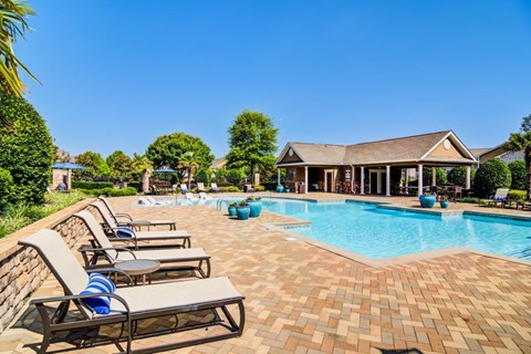 a pool with lounge chairs and a house in the background