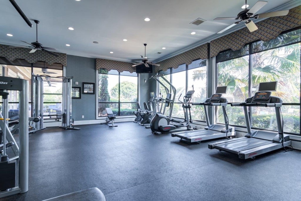 a gym with cardio equipment and windows in a building