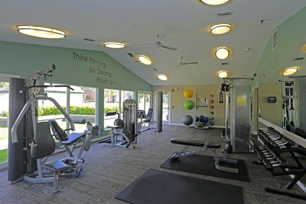 A gym with a variety of equipment and a motivational quote on the wall.