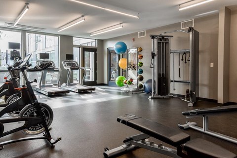 A gym with a variety of equipment including treadmills, exercise balls, and weight machines.