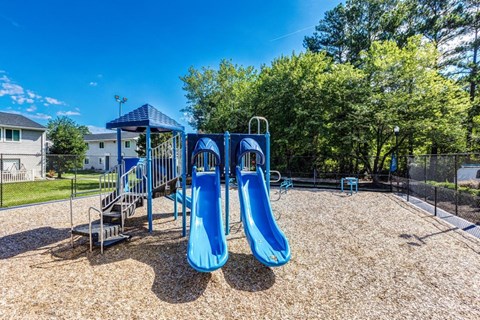 A playground with a blue slide and a blue canopy.