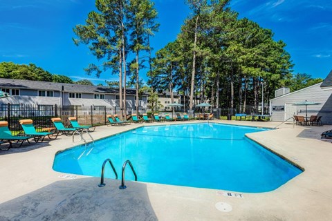 A large outdoor swimming pool surrounded by trees and lounge chairs.