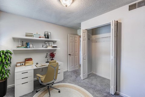 A room with a desk, chair, and a potted plant.