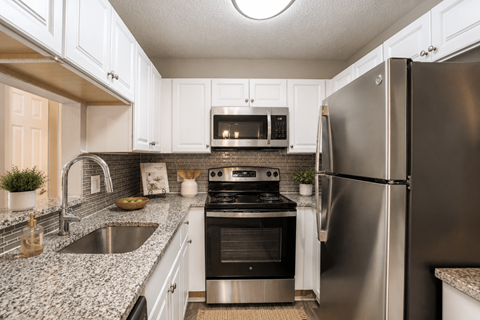 A modern kitchen with a stainless steel refrigerator and a black stove top oven.