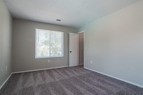 A room with a carpeted floor and a window.