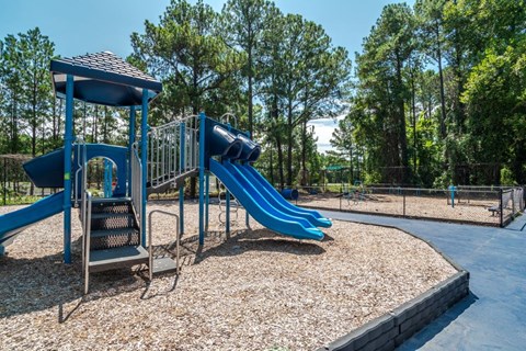 A playground with a blue slide and a small wooden structure.