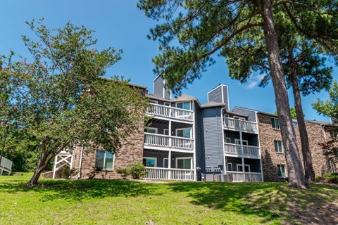 A large apartment building with balconies and a tree in front.