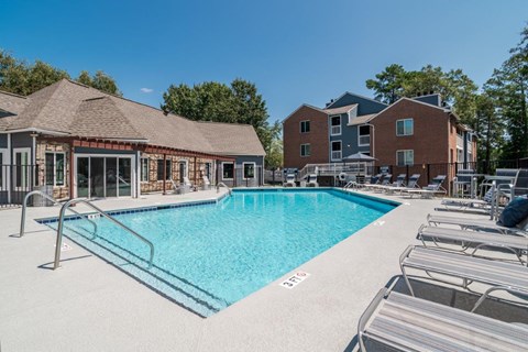 A swimming pool with lounge chairs and a building in the background.