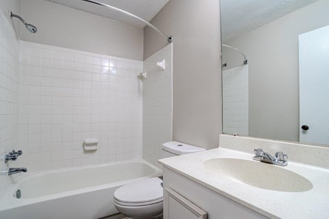 A white bathroom with a toilet, sink, and bathtub.