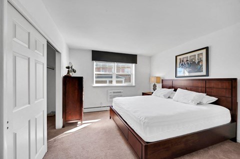 A bedroom with a large bed and a picture on the wall.