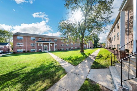 a large brick building with a lawn and trees in front of it
