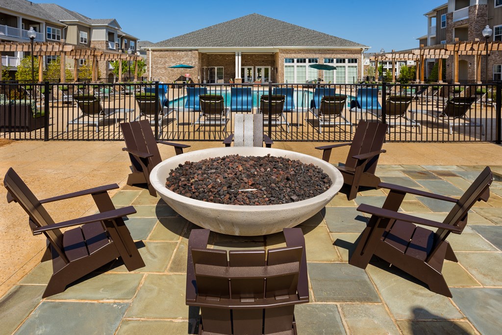 a fire pit with chairs in front of a pool