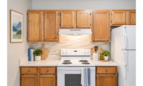 A kitchen with wooden cabinets and a white stove top oven.