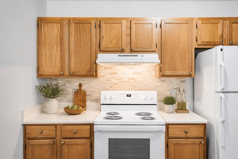 A kitchen with wooden cabinets and a white stove top oven.