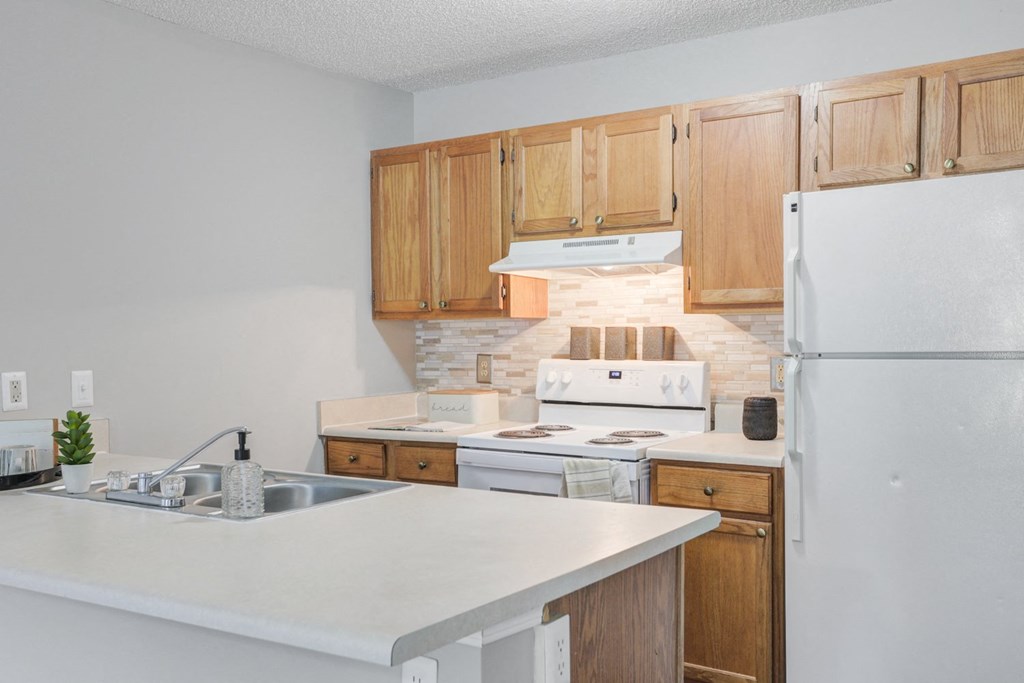 an empty kitchen with wooden cabinets and a white counter top