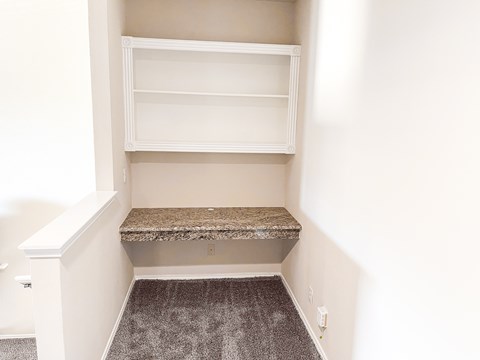 A white shelving unit with a granite bench in a corner of a room.