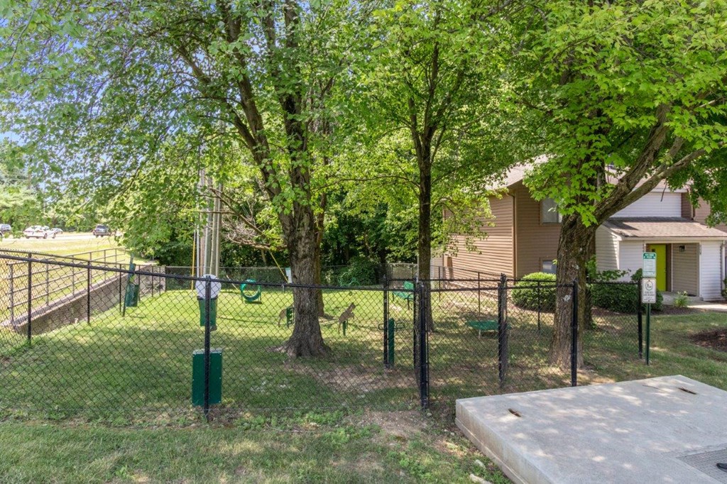 a fenced in yard with trees and a house in the background
