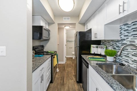 A kitchen with a black refrigerator and a black microwave.
