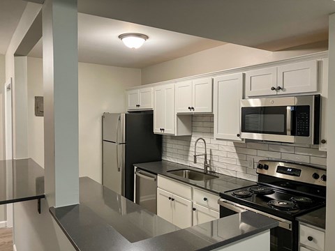 A kitchen with black appliances and white cabinets.